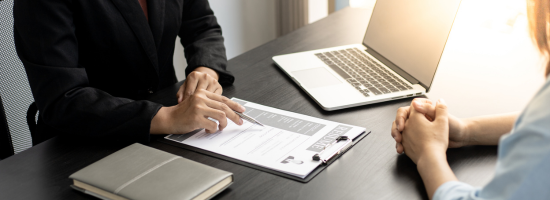 Two individuals meeting over a Resume on a desk in front of them